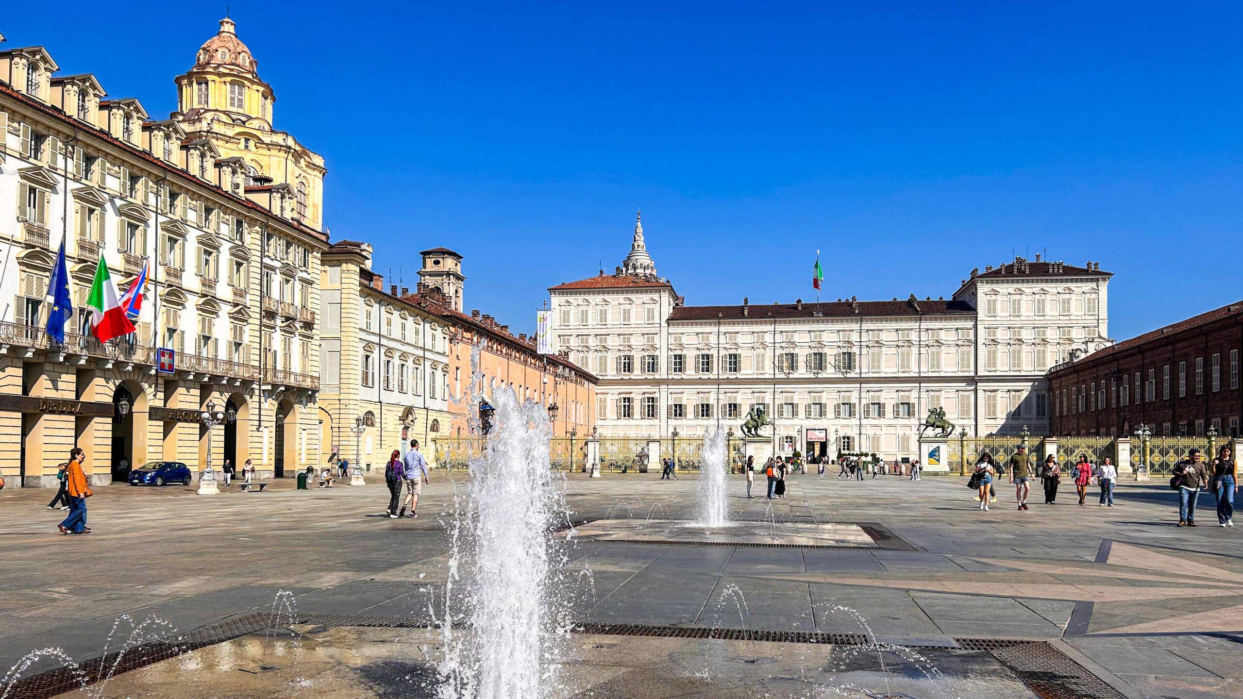 grande piazza di Torino con getti d'acqua dal pavimento circondata da palazzi storici reali